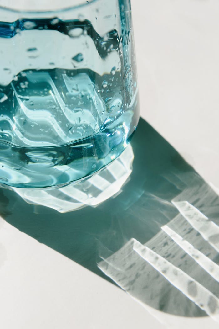 Aesthetic close-up of a blue glass bottle casting a patterned shadow on a light surface.